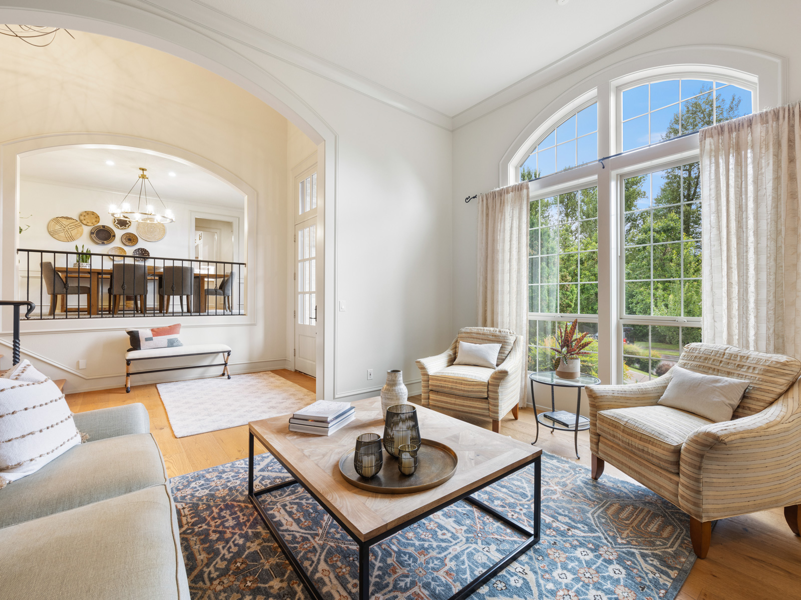 Bright living room with tall arched windows and a view of trees